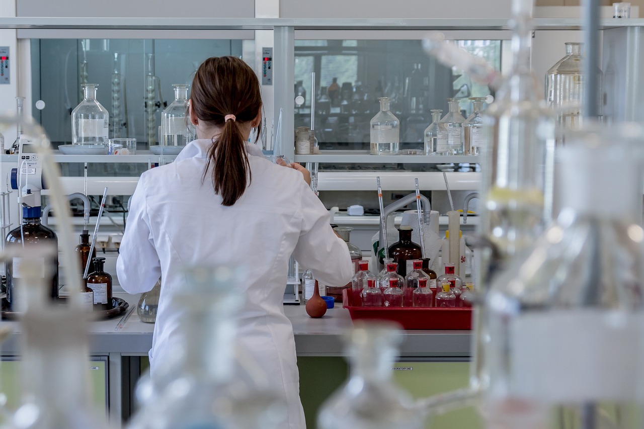 A woman working in a laboratory with a lot of bottles.