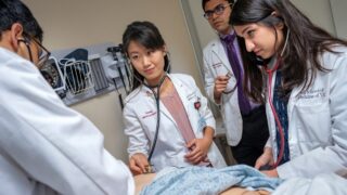 Three medical students working with faculty.