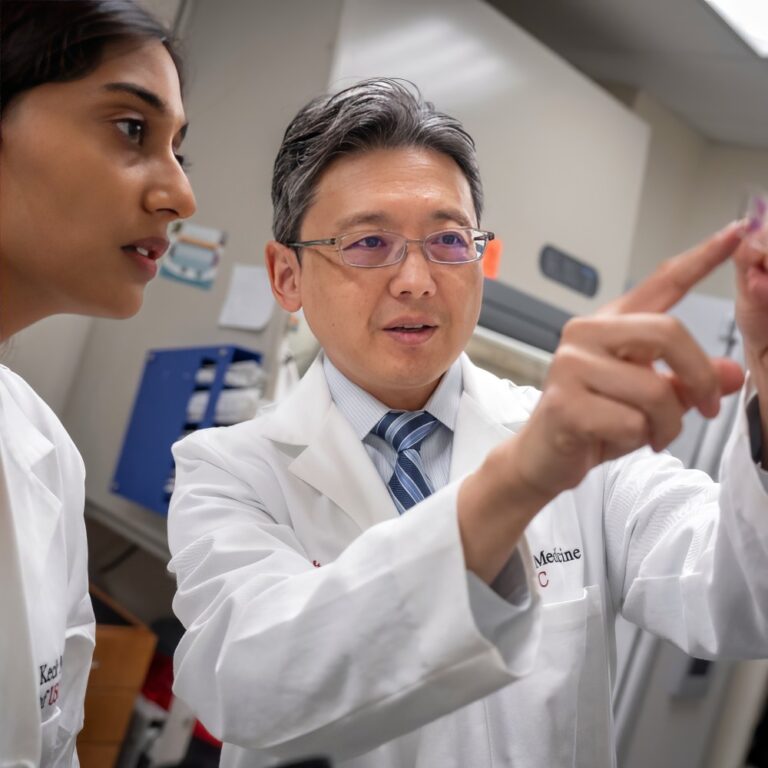 Faculty and student confer over a purple stained slide