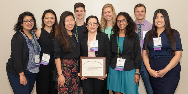 Medical students stand in group with award.