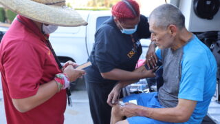 Patient gets blood pressure taken on the street by MA and nurse on Street Medicine.