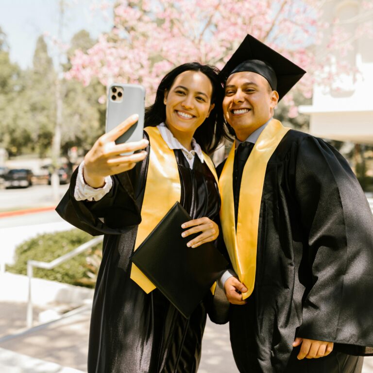 Students taking a selfie in commencement wear.