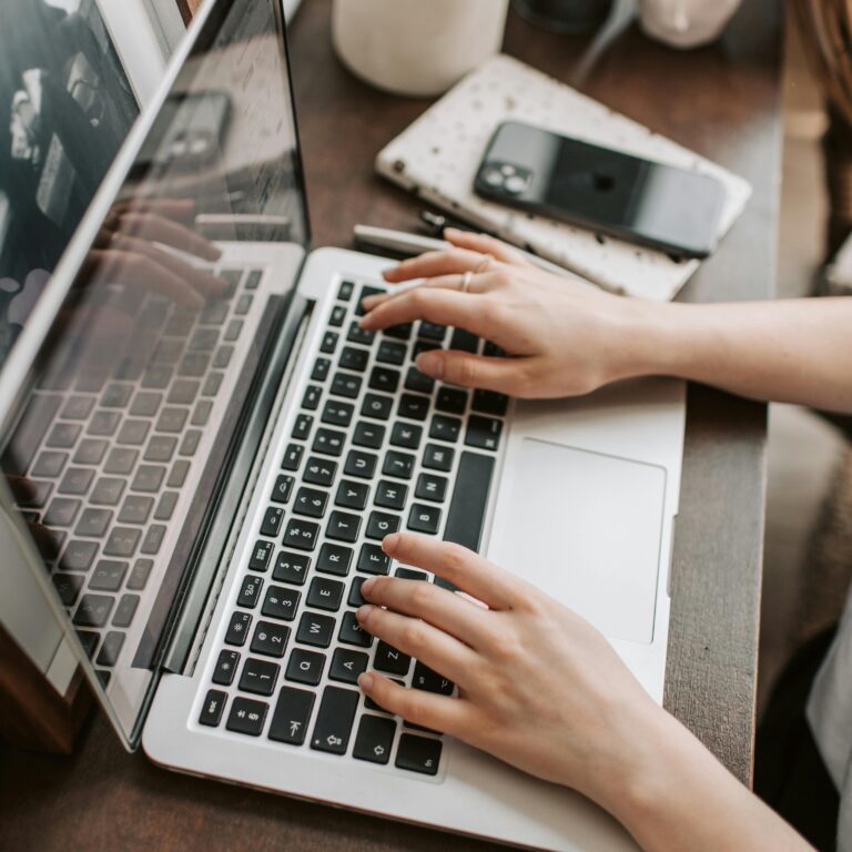 Hands typing on a laptop