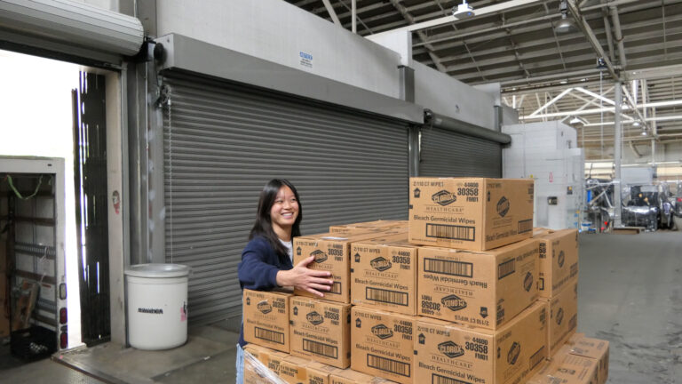 smiling young woman moving boxes in warehouse