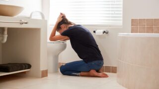 woman vomiting in toilet
