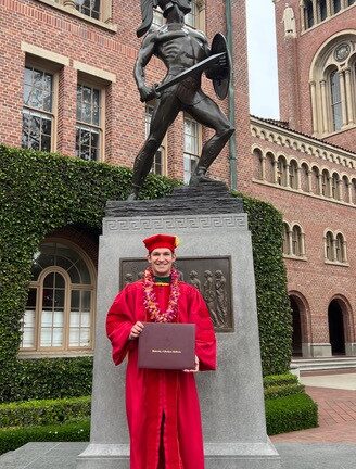 Student in graduation regalia looking at the camera smiling