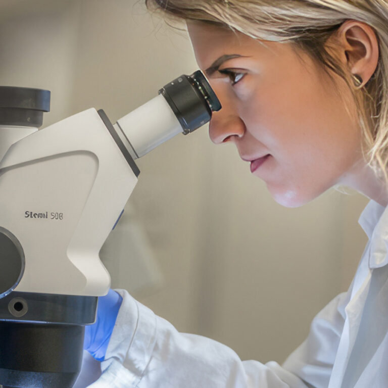 Researcher looks through microscope