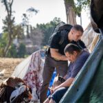 Brett J. Feldman, left, director and co-founder of USC Street Medicine, offers medical care to an unsheltered homeless man. A certified physician assistant, he is an associate professor of medicine at USC and a board member of the Street Medicine Institute. Photo by Chris Shinn/USC