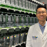 Dr. Kuo stands before banks of Zebrafish tanks, which he uses to seek improved treatments for Ewing sarcoma. (Photo by Dr. Julie Ma)