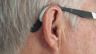 Image of a hearing aid in an elder person's ear.