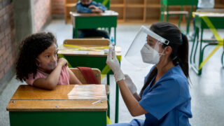 Latin American nurse preparing a COVID-19 vaccine during a vaccination day at school - pandemic concepts