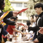Students lined up at the table reaching for their envelopes from Keck staff