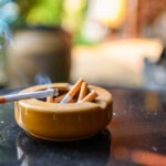 Photo shows cigarette burning in ashtray.