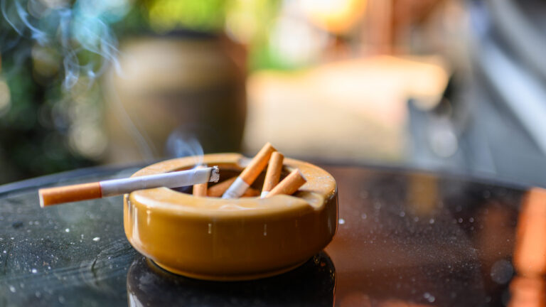 Photo shows cigarette burning in ashtray.