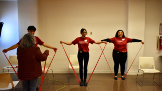 Students standing at the front of the class teaching how to use resistance bands
