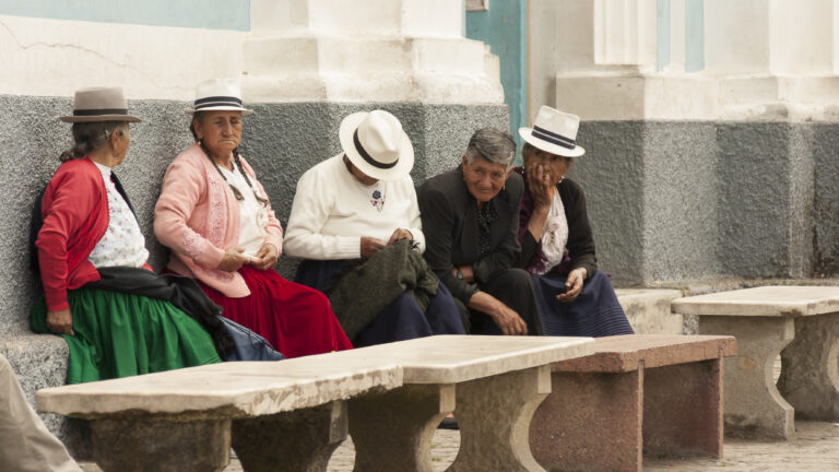 Andean indigenous aged people peacefully sitting on a street in the andean town Baños of Cuenca.