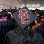 SC written on graduation cap of student in crowd of graduates