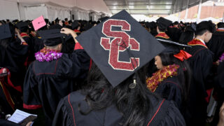 SC written on graduation cap of student in crowd of graduates
