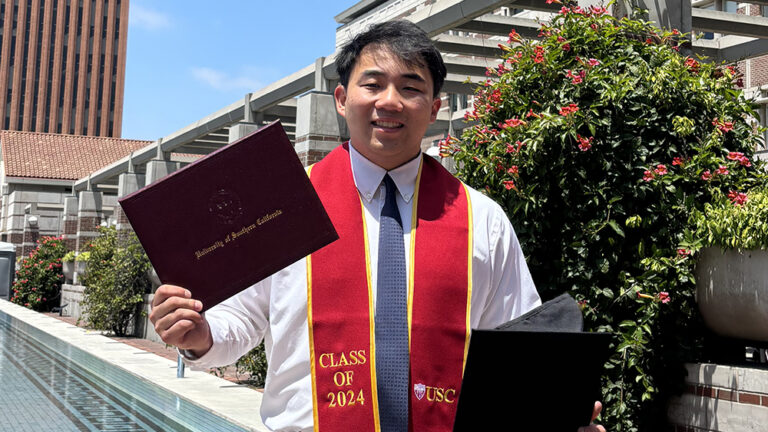Image of Christian Chung holding his diploma and graduation cap