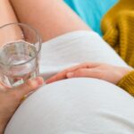 Photo shows pregnant woman with a glass of water.