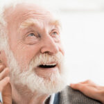 Elderly man with hearing aid talking to doctor