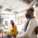 Senior woman in group therapy at a coworking - wearing a face mask
