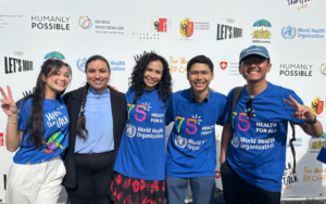 students post for a group picture in front of backdrop at event