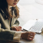 Closeup of young woman using her computer to take notes