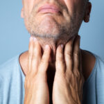 Man with his hands on his throat