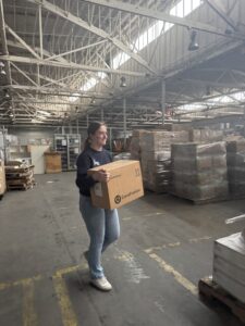 young woman carrying a box in a warehouse