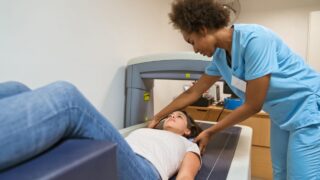 Photo shows female nurse preparing woman for bone density scan.