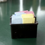 A black square container filled with an assortment of colorful artificial sweetener packets.