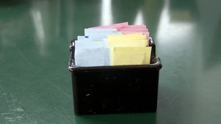 A black square container filled with an assortment of colorful artificial sweetener packets.
