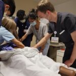 A group of resident students practicing on a mannequin in a skills lab