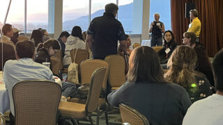People sitting in chairs, with a large window behind them.