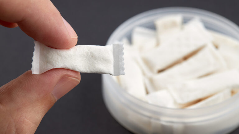 Caucasian person holds snus tobacco pouch over black background. copy space. alternative chewing nicotine smoking.