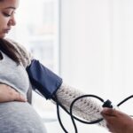 Photo shows a pregnant woman having her blood pressure taken at a clinic.