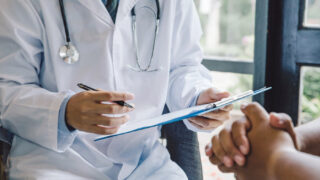 A doctor talks to a patient while holding a clipboard