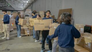 Students in a warehouse working together and carrying boxes of medical equipment
