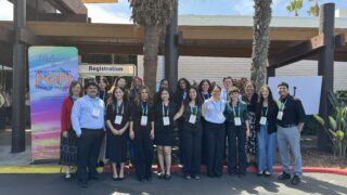 A group of students and faculty pose together wearing their conference badges