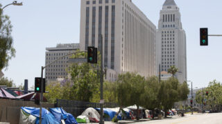 A massive tent encampment of homeless individuals on a Downtown Los Angeles sidewalk.