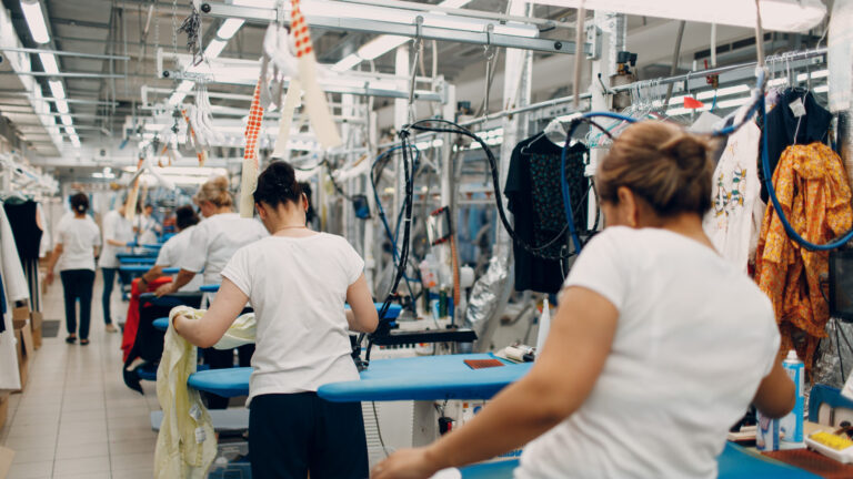 Factory scene with women sorting and arranging clothes on racks
