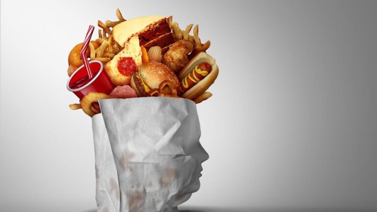 Image shows ultra-processed snacks and fast food in a greasy bag that forms the profile of a person who is overweight.