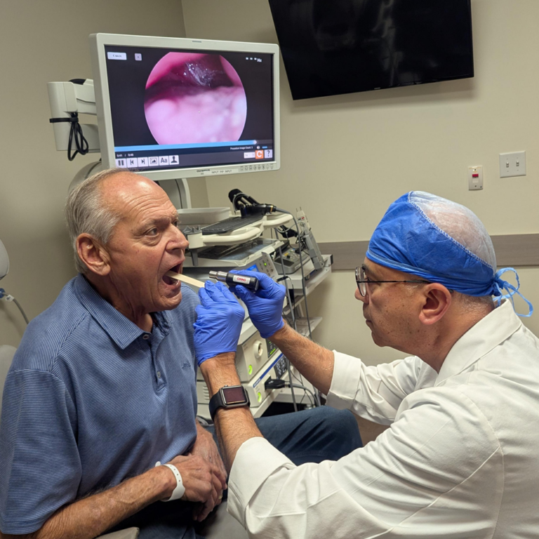 A patient being examined in the oral cavity and throat by Dr. Uttam Sinha in the exam room.