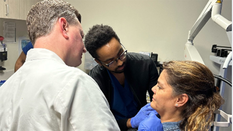 Faculty, resident, and patient at the facial injection workshop.