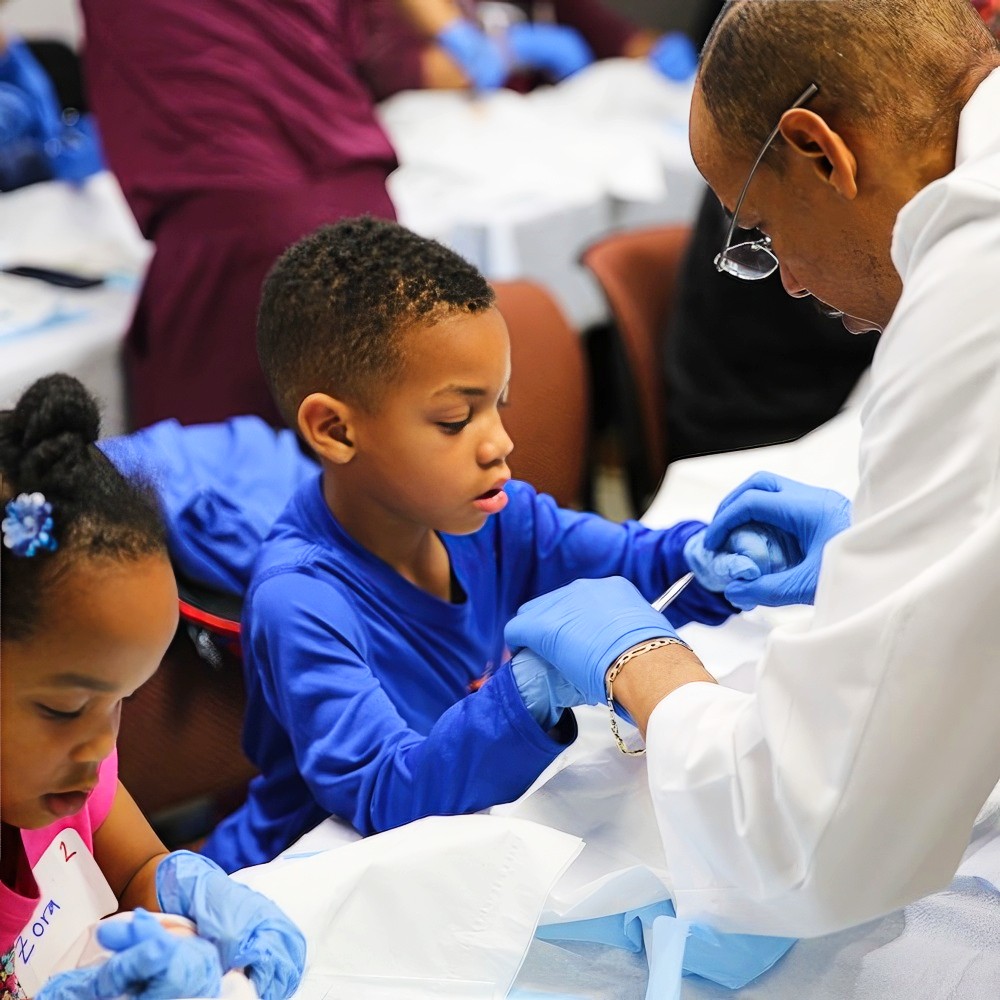 PA works with childrens,showing them how sutures are made.