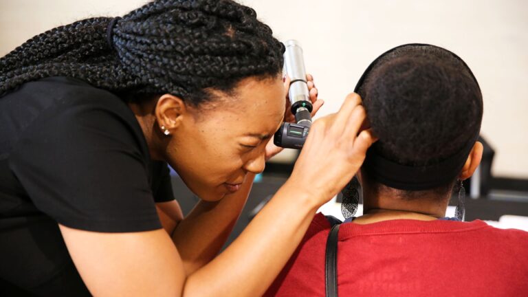 Physician Assistant program student examines the ear of a female patient.