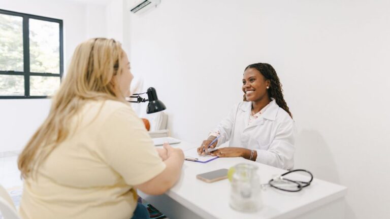 Photo shows teenager who is overweight talking to her doctor.
