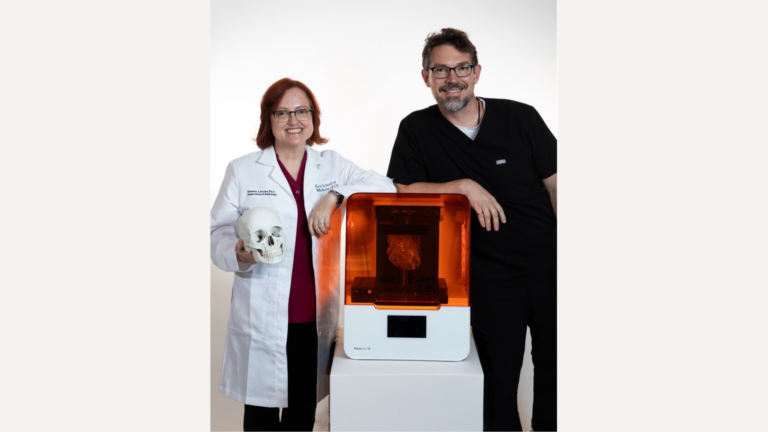 Photo of Summer Decker (left) and Jonathan Ford (right) standing beside a 3D printer