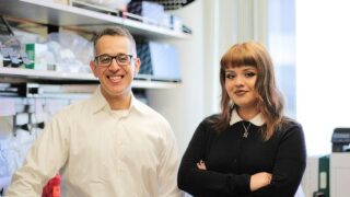 Members of a faculty lab in front of their equipment and bench.